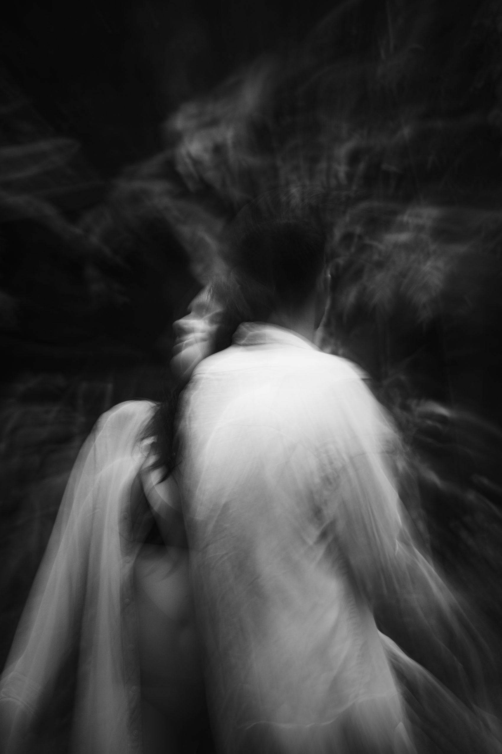 Two dancers folded together in low light, black and white